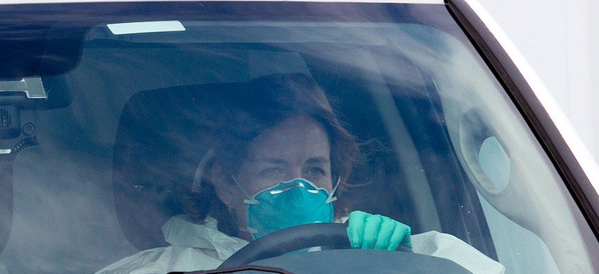 A woman in protective clothing drives an ambulance after departing Dobbins Air Reserve Base in Marietta., Ga., en route Emory University Hospital, carrying Ebola patient Dr. Kent Brantly.
