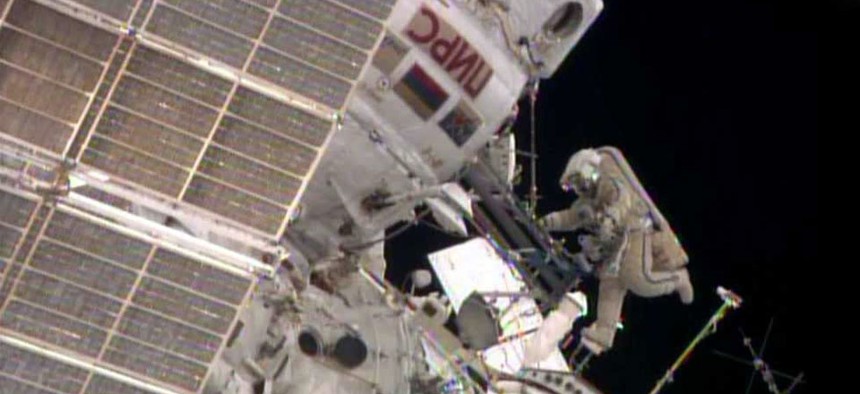 While Flight Engineer Alexander Skvortsov retrieves hardware inside the International Space Station's Pirs airlock, Flight Engineer Oleg Artemyev stretches his legs.