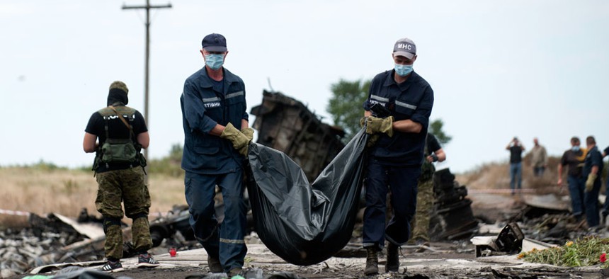 Ukrainian emergency workers carry a victim's body in a bag, at the crash site of Malaysia Airlines Flight 17 near the village of Hrabove, eastern Ukraine