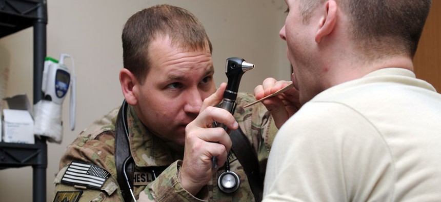 Army Maj. (Dr.) Tim Cheslock examines a patient and fellow soldier at the primary care New Kabul Compound clinic in Afghanistan.