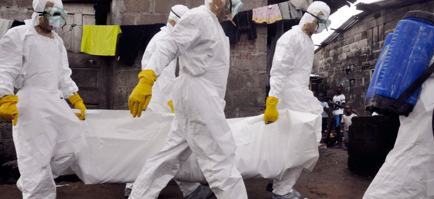 Health workers carry the body of a woman that they suspect died from the Ebola virus.