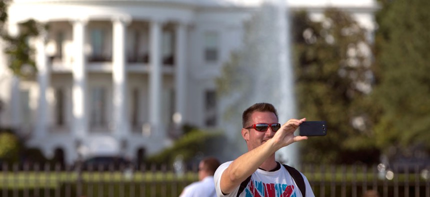 A man takes a selfie with the White House in Washington, DC.
