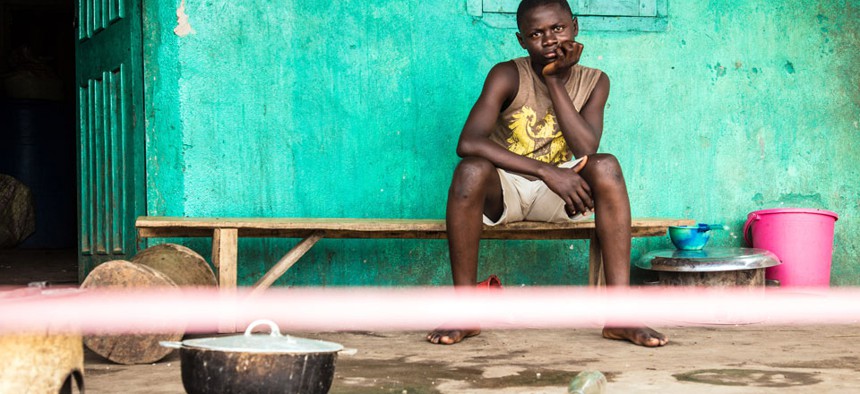 A youth under quarantine sits behind a cordon outside his house in Moyamba town on the outskirts of Freetown, Sierra Leone.