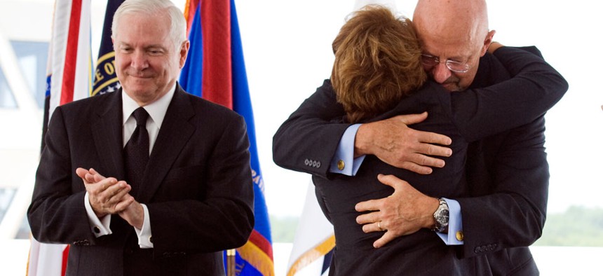 Defense Secretary Robert Gates, left, applaud as Letitia Long, center, is hugged by James Clapper, director, National Intelligence, center, after becoming the new Director of the National Geospatial-Inteligence Agency, Monday, Aug. 9, 2010.