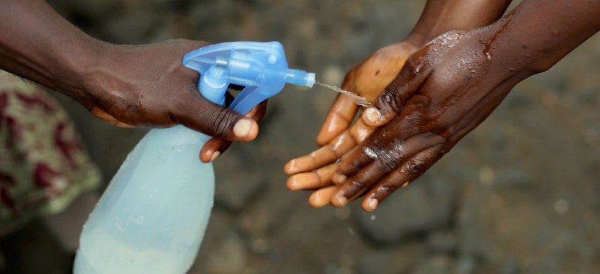 Promise Cooper, 16, gets her hands cleaned with a chlorine solution by Kanyean Molton Farley, a community activist  in Monrovia, Liberia.