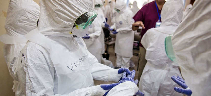 A World Health Organization, WHO, worker, right rear, trains nurses to use Ebola protective gear in Freetown, Sierra Leone.