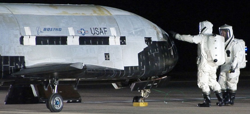 Technicians examining the X-37B unmanned spaceplane shortly after landing Friday Dec. 3, 2010 at Vandenberg Air Force Base, Calif.