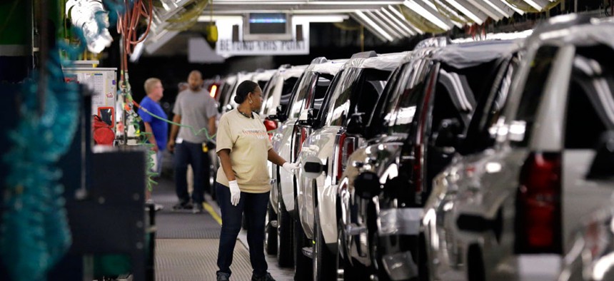 An auto worker inspects finished SUVs coming off the assembly line at the General Motors auto plant in Arlington, Texas.