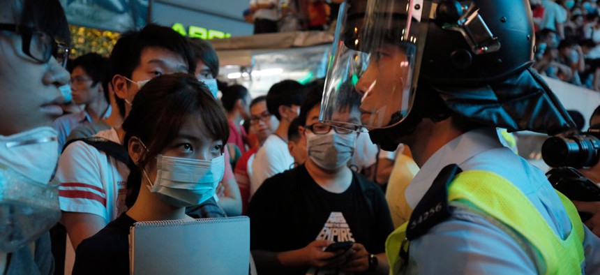 Riot police officers stand guard against protesters at a main road in the Mong Kok district of Hong Kong Friday, Oct. 17, 2014.