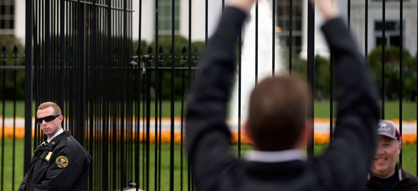 A Secret Service police officer keeps an eye on visitors on the sidewalk in front of the White House in Washington.