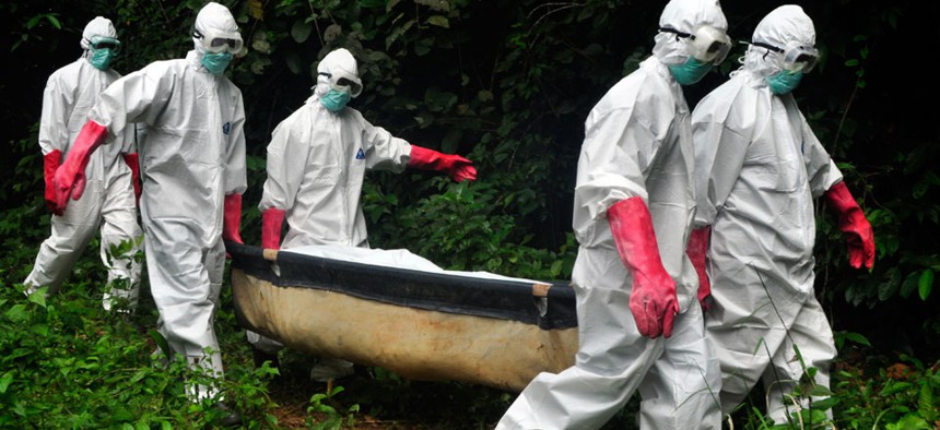 A burial team in protective gear carry the body of woman suspected to have died from the Ebola virus in Monrovia, Liberia. 