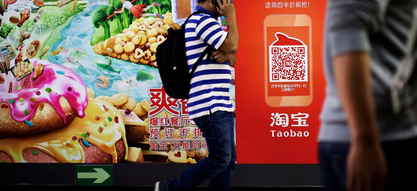 A Chinese man talks on a mobile phone as he walks past a Taobao's mobile app advertisement billboard on display inside a subway station in Beijing.