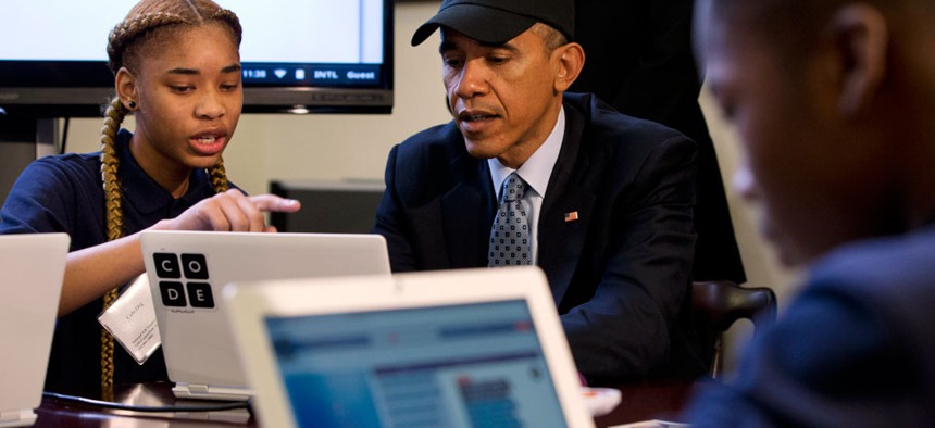 President Barack Obama is explained a coding learning program by Adrianna Mitchell during an “Hour of Code” event 