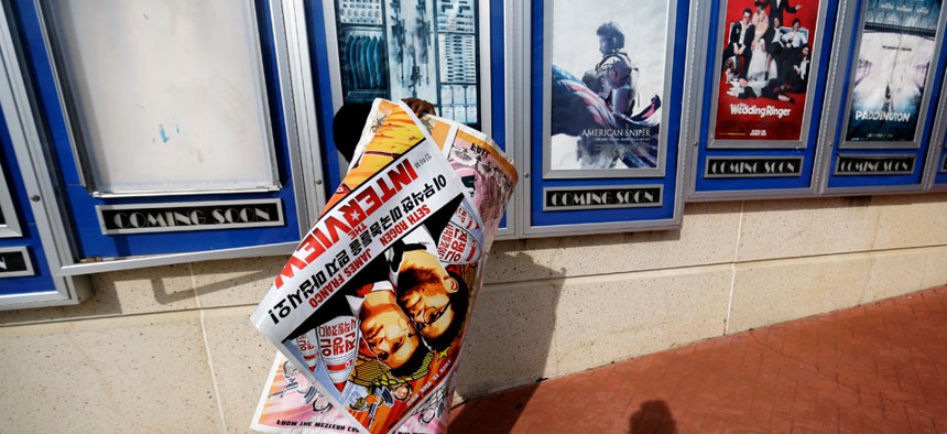 A poster for the movie "The Interview" is carried away by a worker after being pulled from a display case at a Carmike Cinemas movie theater, Wednesday, Dec. 17, 2014.