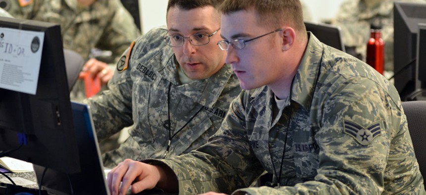 Army Sgt. 1st Class Michael Deblock, Vermont Army National Guard Computer Network Defense Team, left, discusses new ways to make the exercise more challenging for cyber defenders with a fellow Red Cell team member during the 2014 Cyber Shield exercise.