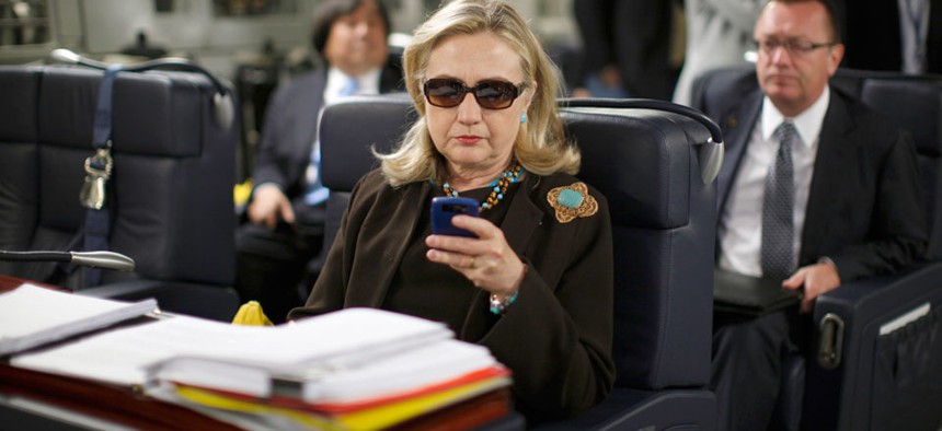 Then-Secretary of State Hillary Rodham Clinton checks her Blackberry from a desk inside a C-17 military plane upon her departure from Malta.