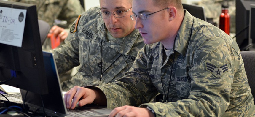 Army Sgt. 1st Class Michael Deblock, Vermont Army National Guard Computer Network Defense Team, left, discusses new ways to make the exercise more challenging for cyber defenders with a fellow Red Cell team member during a 2014 Cyber Shield exercise.