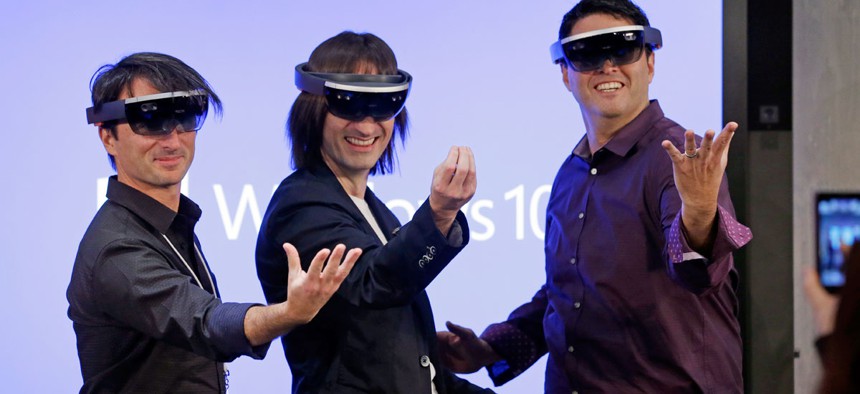 Microsoft's Joe Belfiore, from left, Alex Kipman, and Terry Myerson playfully pose for a photo while wearing "Hololens" devices.