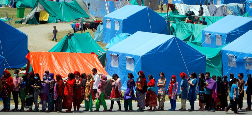 People who have had their homes damaged and are living in tents during the April 25 earthquake line up for drinking water and packed noodles in Kathmandu, Nepal.