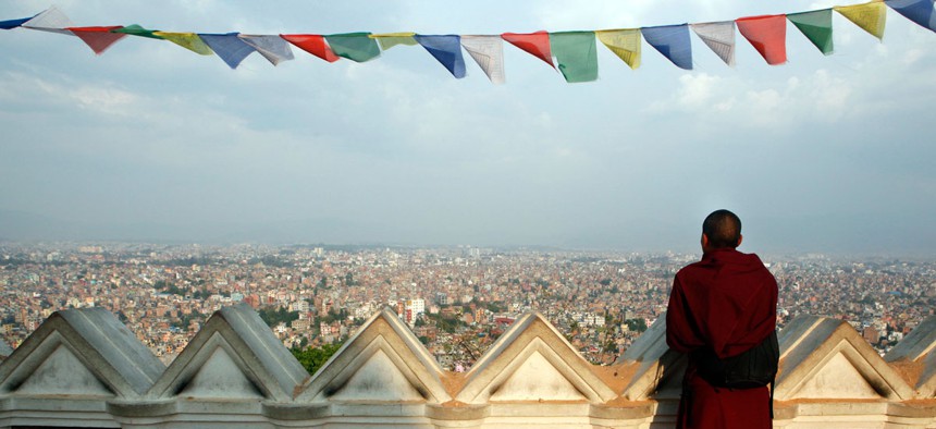 A Buddhist monk catches an aerial view of Kathmandu from the damaged Swayambhunath Stupa premises in Kathmandu, Nepal.