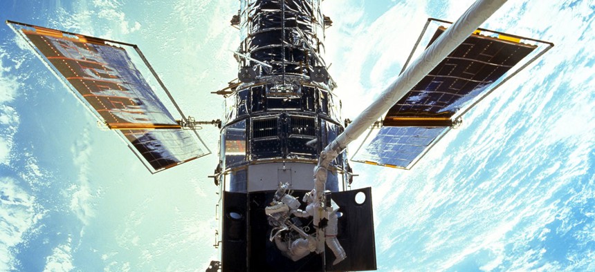 Astronauts Steven L. Smith and John M. Grunsfeld are photographed during an extravehicular activity (EVA) during the December 1999 Hubble servicing mission of STS-103, flown by Discovery.