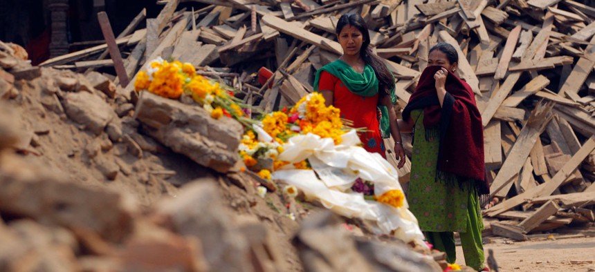 Nepalese women look at floral tributes placed in memory of victims killed in the earthquake, at Basantapur Durbar Square in Kathmandu, Nepal, Thursday, May 7, 2015.