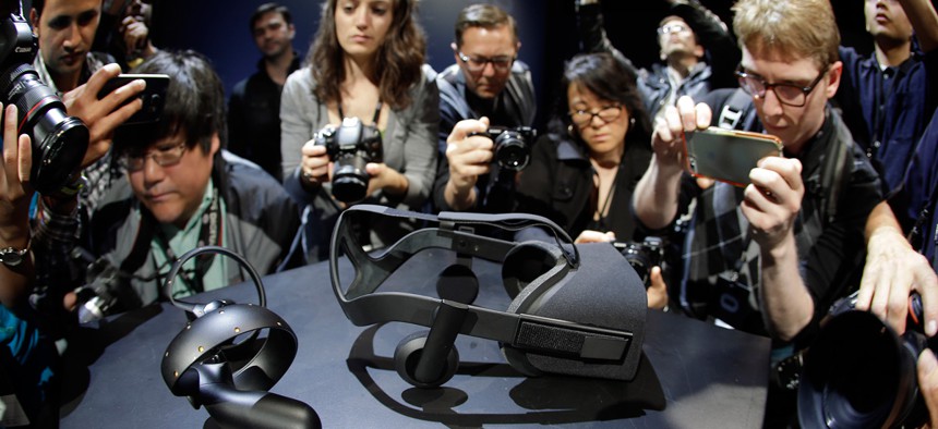 Photographers take pictures of the new Oculus Rift virtual reality headset and touch input device.
