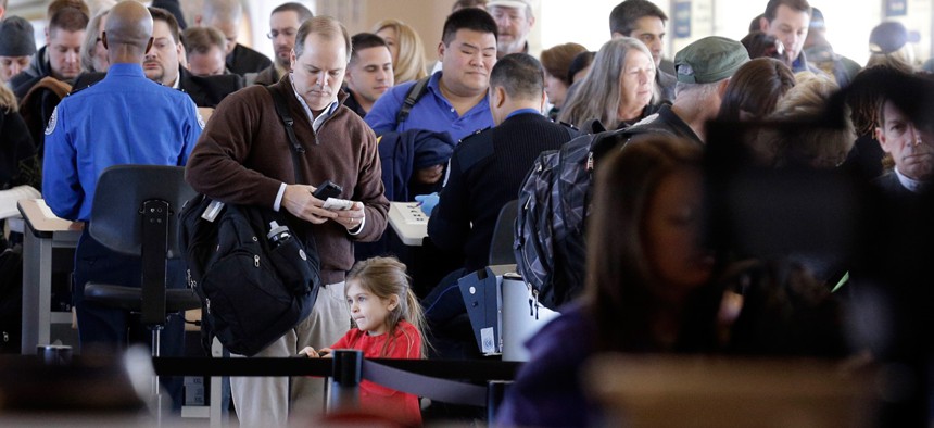 Travelers wait in line to check in at a security checkpoint area at Midway International Airport.