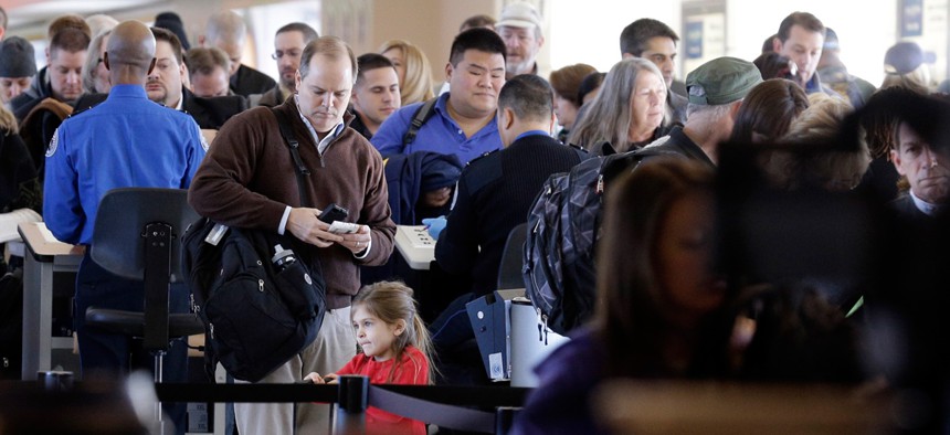 Travelers wait in line to check in at a security checkpoint area at Midway International Airport, Friday, Nov. 21, 2014, in Chicago.