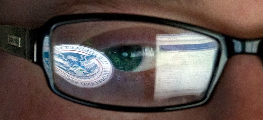 A reflection of the DHS logo is seen reflected in the glasses of a cybersecurity analyst in the watch and warning center at DHS' secretive cyber defense facility in Idaho.