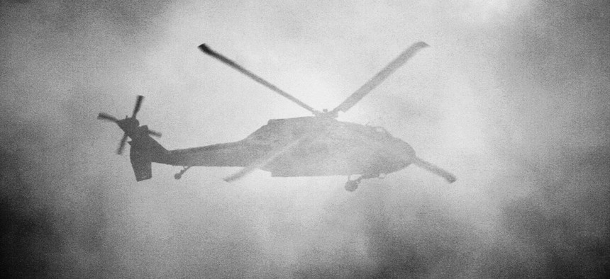 A United States Army Sikorsky UH-60 Blackhawk flies behind a cloud of smoke.