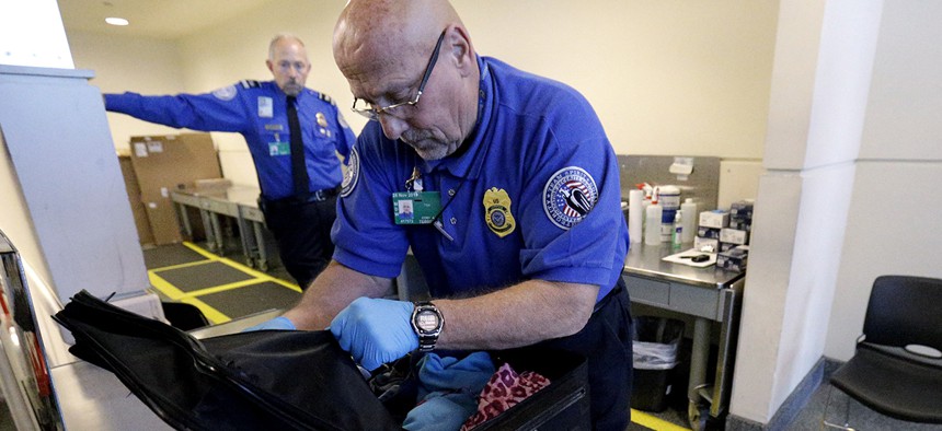 A TSA agent checks a bag at a security checkpoint area at Midway International Airport.