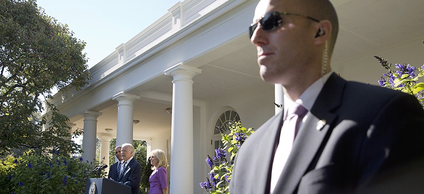 A Secret Service Agent stands guard as Vice President Joe Biden, with President Barack Obama and his wife Jill Biden, speaks in the Rose Garden of the White House.