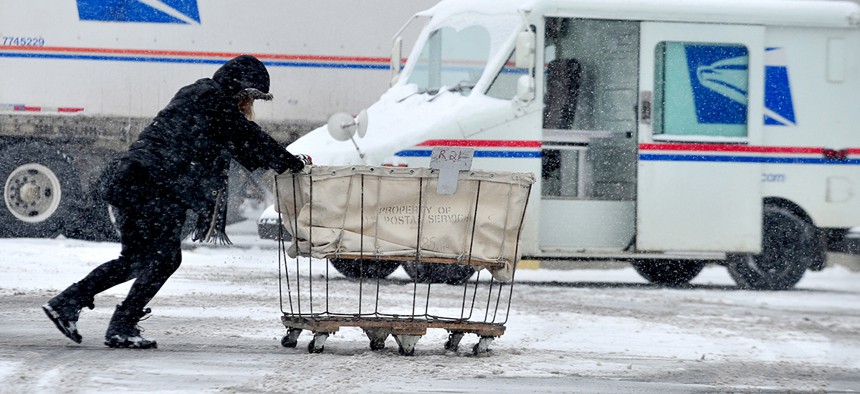 USPS carrier Stephanie Starr, of Seymour, pushes a mail cart from her carrier vehicle to the loading dock area of the Columbus, Ind. Post Office.