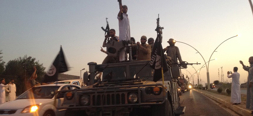 Militants from the Islamic State parade in a commandeered Iraqi security forces armored vehicle on a main street in Mosul, Iraq.