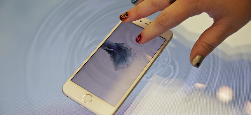 A woman press an Apple iPhone 6s on a 3D touch table at the Apple store Friday, Nov. 13, 2015
