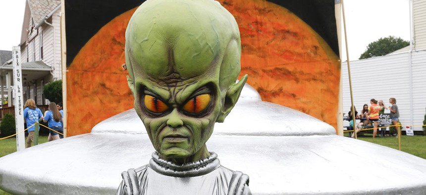 A green alien is positioned in front of the permanent flying saucer replica in Mars, Pa.