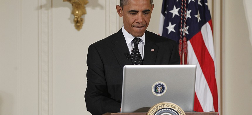 President Barack Obama uses a laptop computer to send a tweet during a "Twitter Town Hall" in the East Room of the White House.