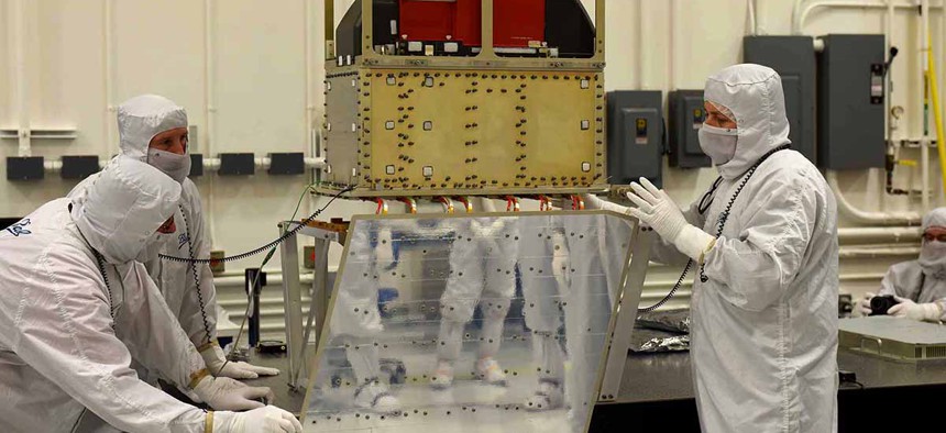 Ball Aerospace technicians lower the ATMS instrument onto the JPSS-1 spacecraft.