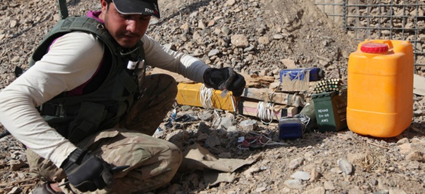 An Afghan Civilian Mine Removal Group member investigates IEDs during a training simulation in Panjwai district, Kandahar province, Afghanistan, Nov. 19, 2013.