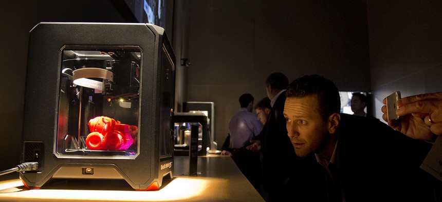 Trade show attendees examine the MakerBot Replicator Mini 3D printer at the International Consumer Electronics Show, Wednesday, Jan. 8, 2014.