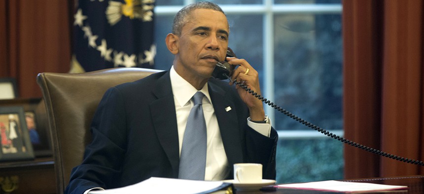 President Obama speaks on a landline phone in the Oval Office.