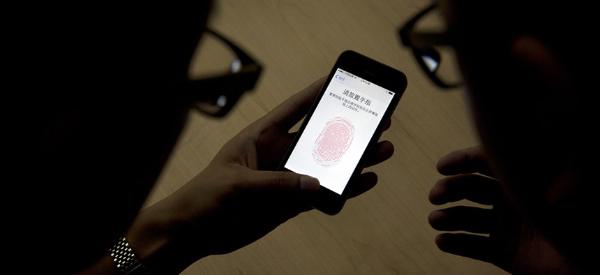 An Apple employee, right, instructs a journalist on the use of the fingerprint scanner technology built into the company's iPhone 5S during a media event in Beijing.