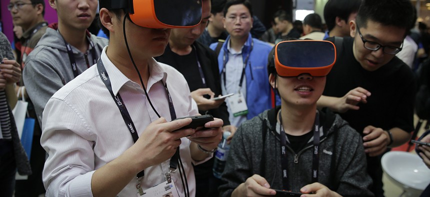 Visitors wearing virtual reality devices play games at a display booth for Qualcomm at the 2016 Global Mobile Internet Conference (GMIC) in Beijing, Thursday, April 28, 2016.