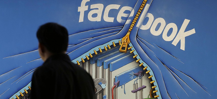 A man walks past a mural in an office on the Facebook campus in Menlo Park, Calif. 