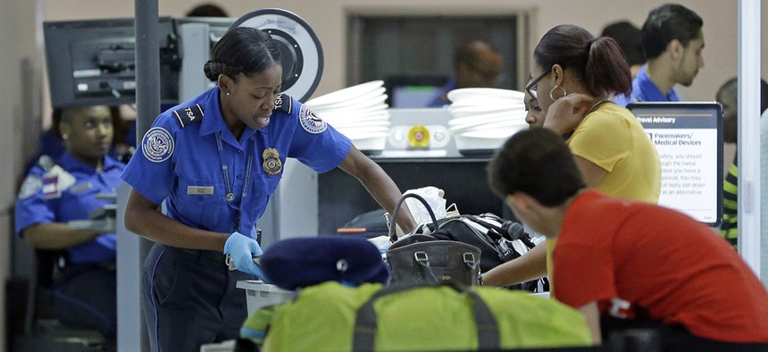 A TSA officer checks travelers luggage to be screened by an x-ray machine at a checkpoint at Fort Lauderdale-Hollywood International Airport.