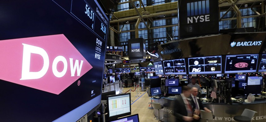 The company names of Dow, left, and Dupont, right, appear above their trading posts on the floor of the New York Stock Exchange.