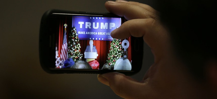 An audience member snaps a cell phone photo as Republican presidential candidate Donald Trump speaks during a campaign rally.