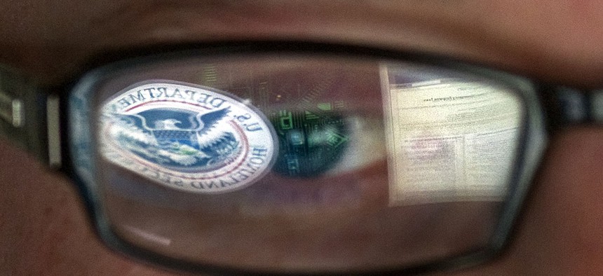 A reflection of the Department of Homeland Security logo is seen reflected in the glasses of a cyber security analyst in the watch and warning center at the Department of Homeland Security's secretive cyber defense facility.