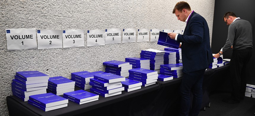 Two men glance through The Iraq Inquiry Report presented by Sir John Chilcot at the Queen Elizabeth II Centre in London, Wednesday, July 6, 2016.